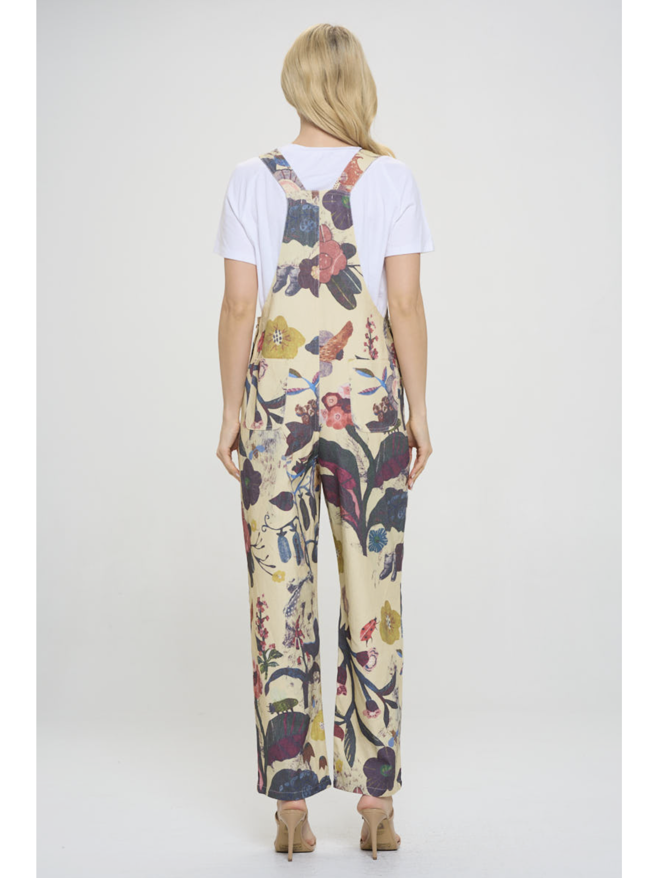 Woman wearing a floral jumpsuit with a plain white background