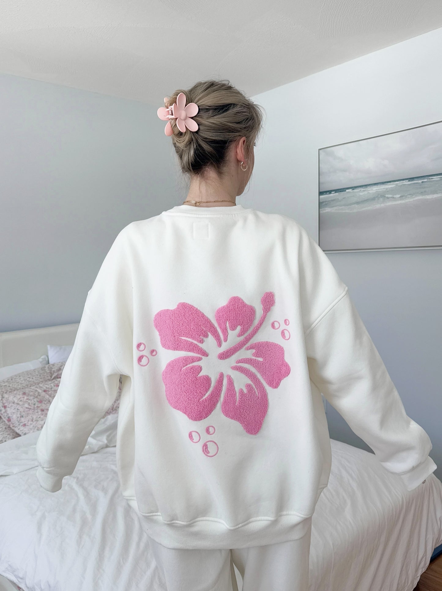 Ivory-colored sweatshirt featuring a vintage-style hibiscus flower graphic, perfect for a relaxed coastal and slow-living aesthetic.