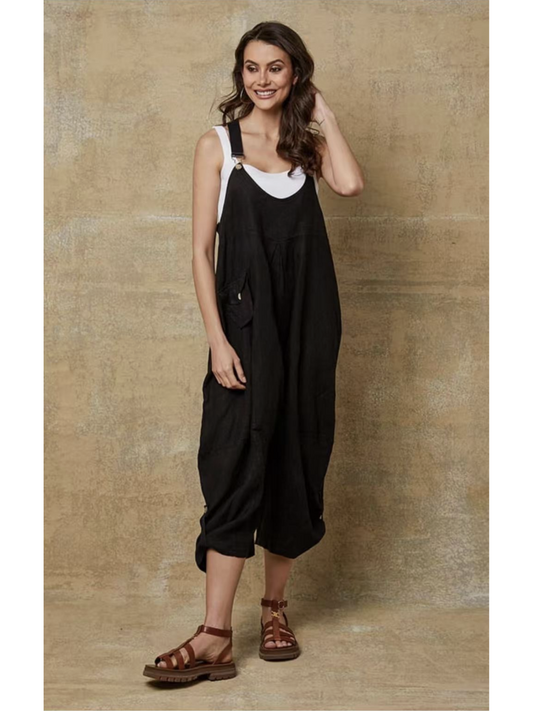 Model in a black 100% linen jumpsuit with a relaxed fit, adjustable buckle straps, and button details at the ankles, over a white tank top.