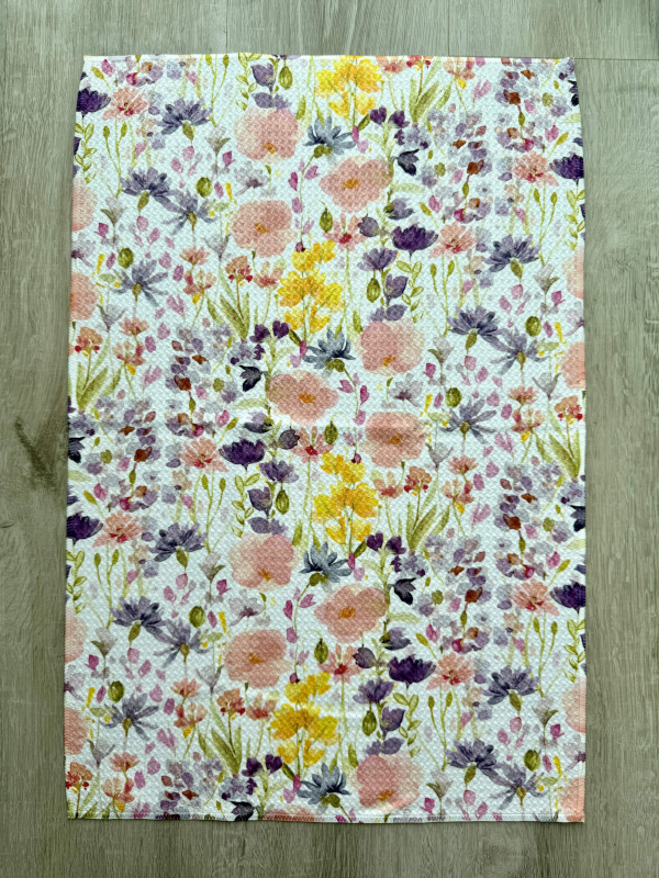 Decorative tea towel featuring a detailed floral print with multiple flowers  on a white background.