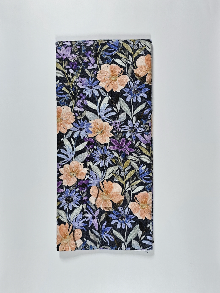 Decorative tea towel featuring a detailed botanical print with peach flowers and purple petals on a dark background.