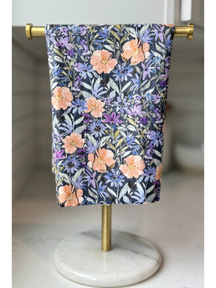Floral-patterned towel hanging on a gold towel rack with a marble base.