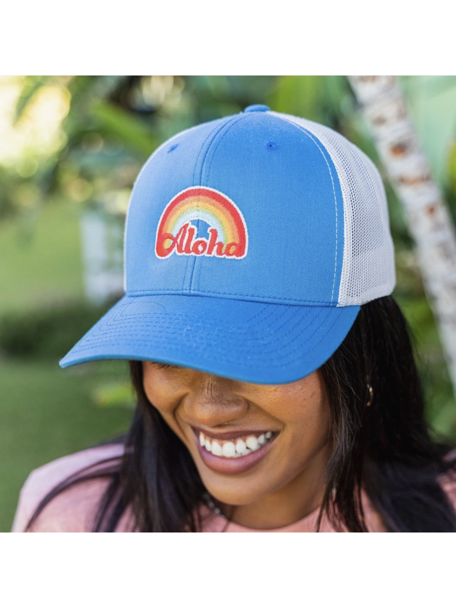 Person wearing a blue cap with 'Aloha' design outdoors