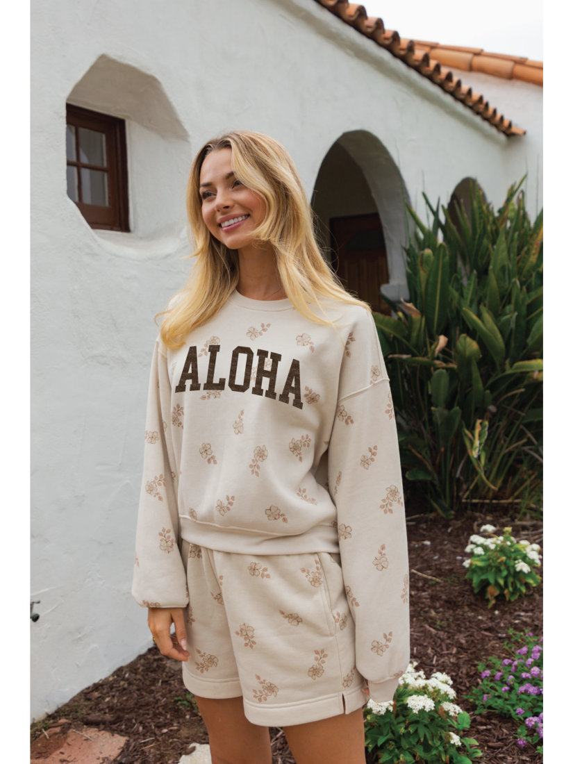 Cozy two-piece matching set in a soft-brushed fabric with a whimsical "Aloha" graphic and a relaxed, soulful coastal aesthetic.