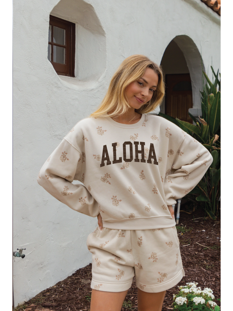 Cozy two-piece matching set in a soft-brushed fabric with a whimsical "Aloha" graphic and a relaxed, soulful coastal aesthetic.