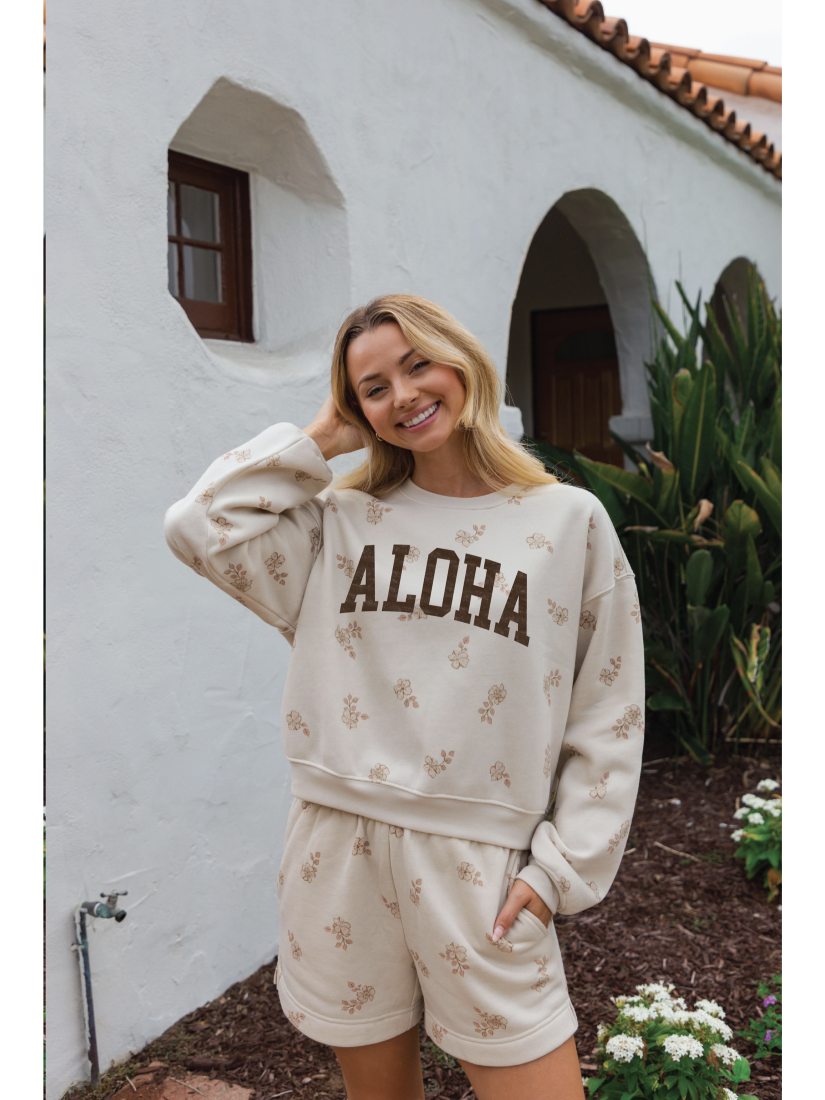 Cozy two-piece matching set in a soft-brushed fabric with a whimsical "Aloha" graphic and a relaxed, soulful coastal aesthetic.
