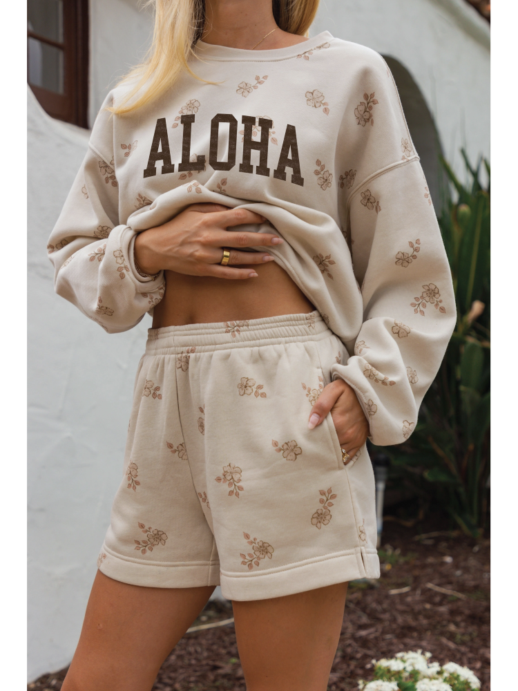 Cozy two-piece matching set in a soft-brushed fabric with a whimsical "Aloha" graphic and a relaxed, soulful coastal aesthetic.