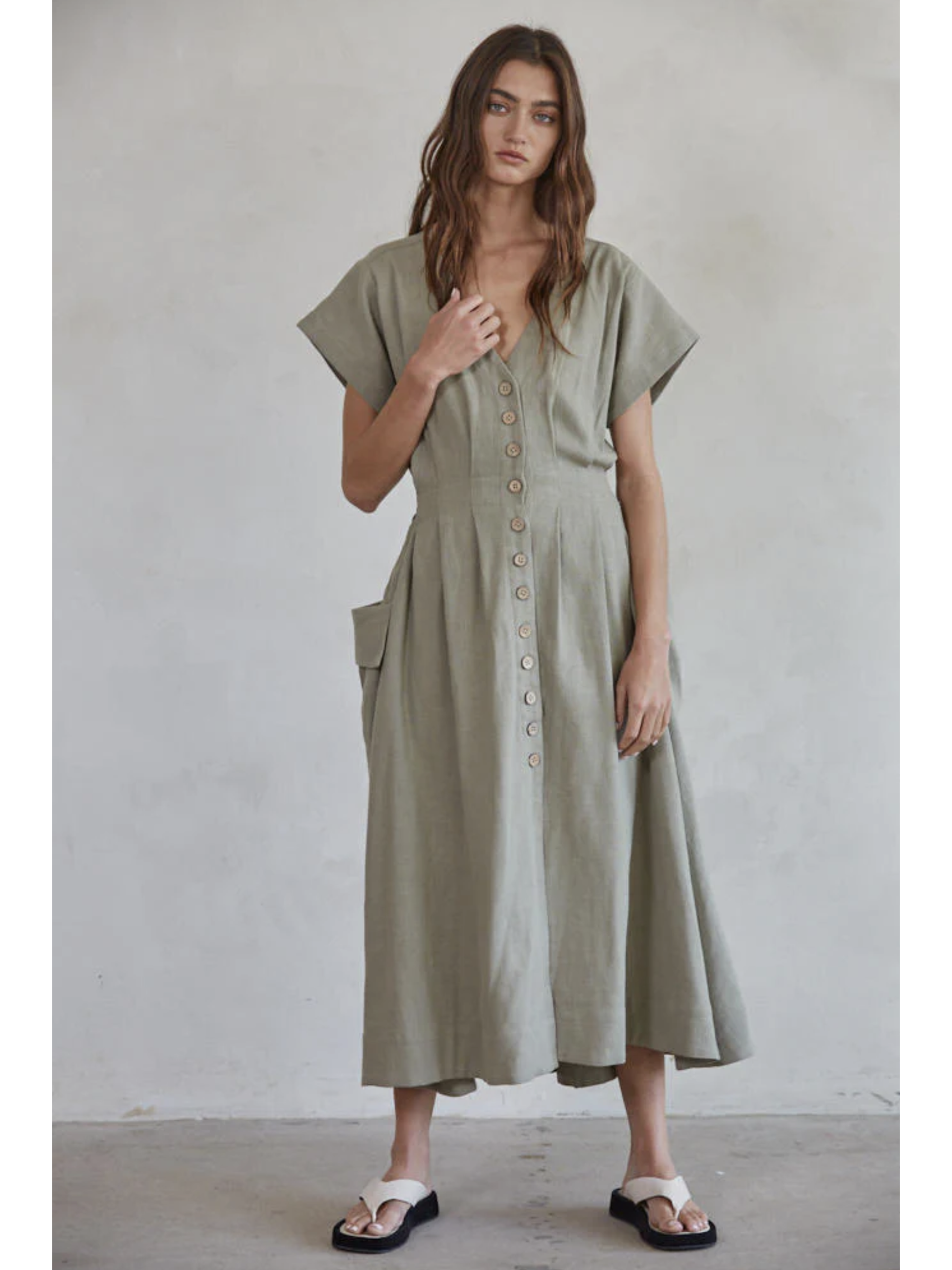 Woman wearing a green dress with button details against a plain background