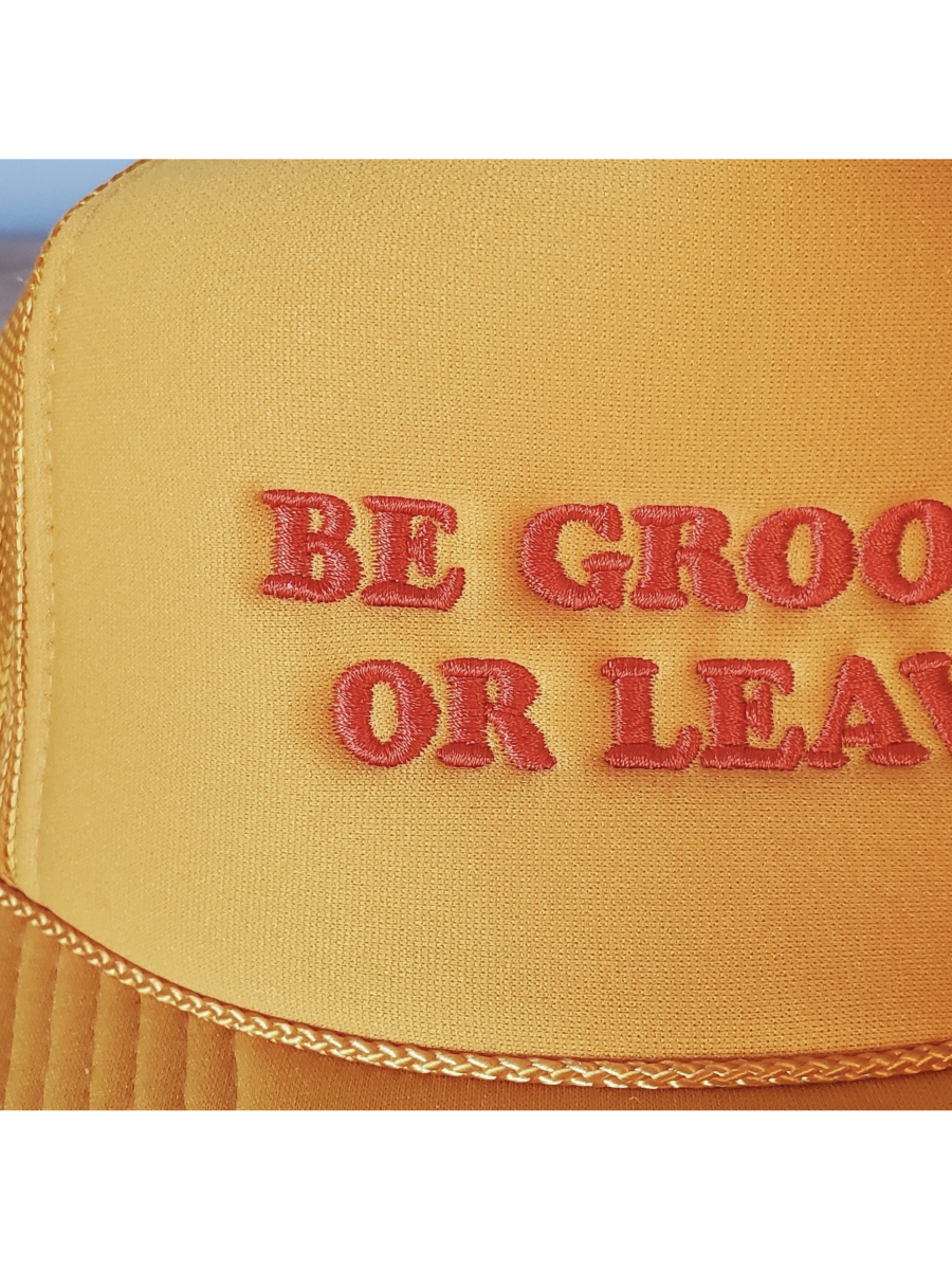 Yellow hat with red text 'BE GROOVY OR LEAVE' on a white background