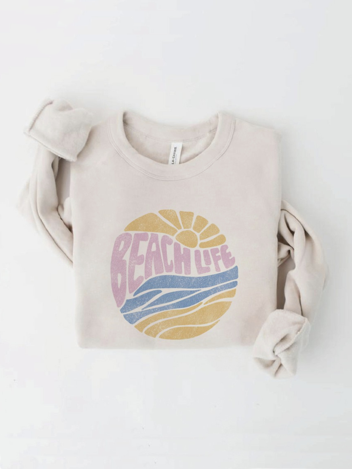 Cream-colored sweatshirt with a circular "Beach Life" graphic featuring a sun and waves in pastel pink, yellow, and blue.