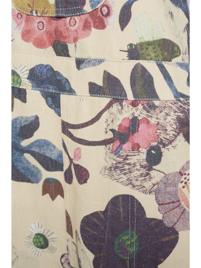 Close-up of a floral patterned fabric with colorful flowers and leaves on a beige background.