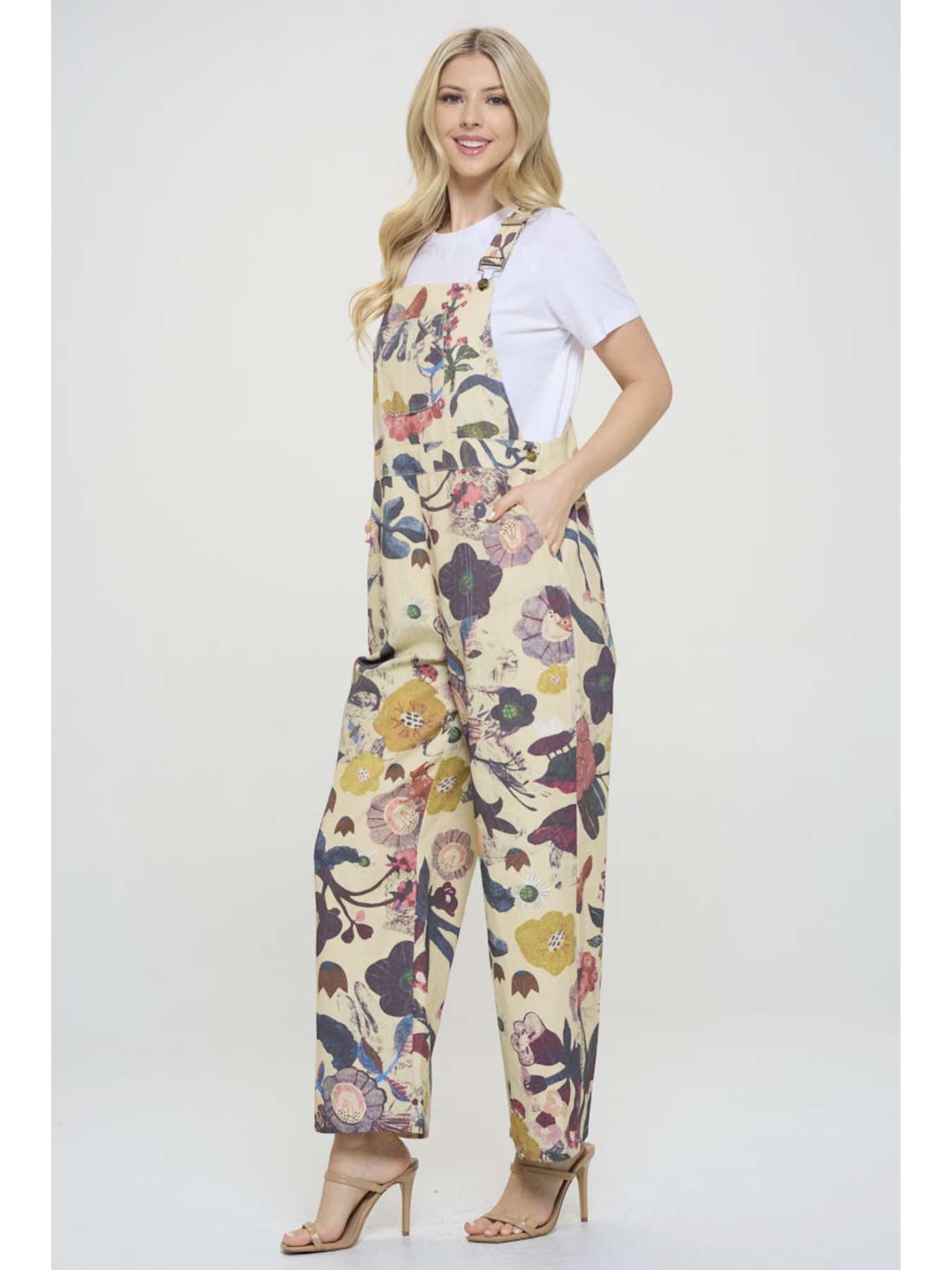 Woman wearing a floral overalls and white shirt on a white background