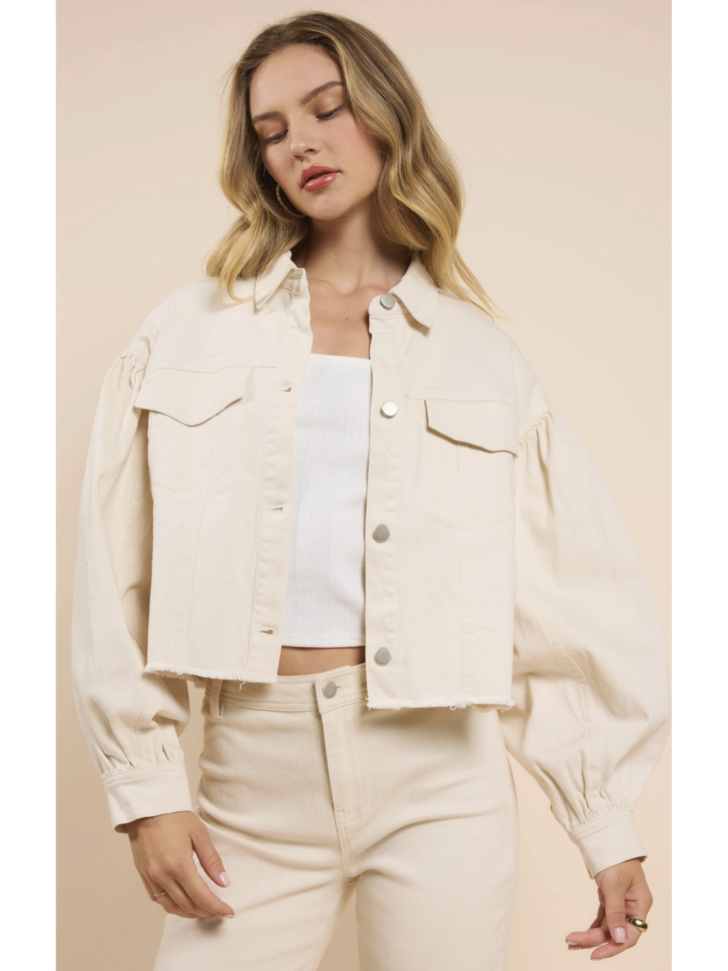 Woman wearing a beige jacket and pants against a beige background