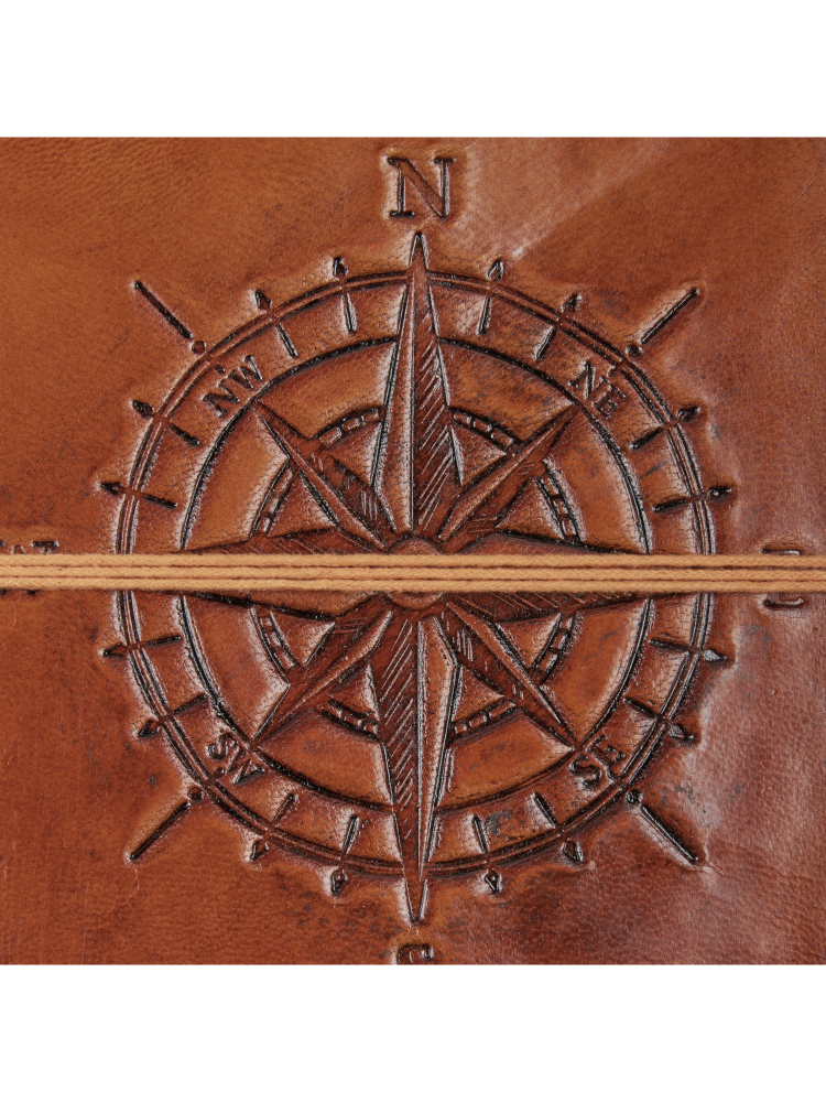 Brown leather journal with an embossed compass rose design and a thin tan elastic band closure, centered on a white background.