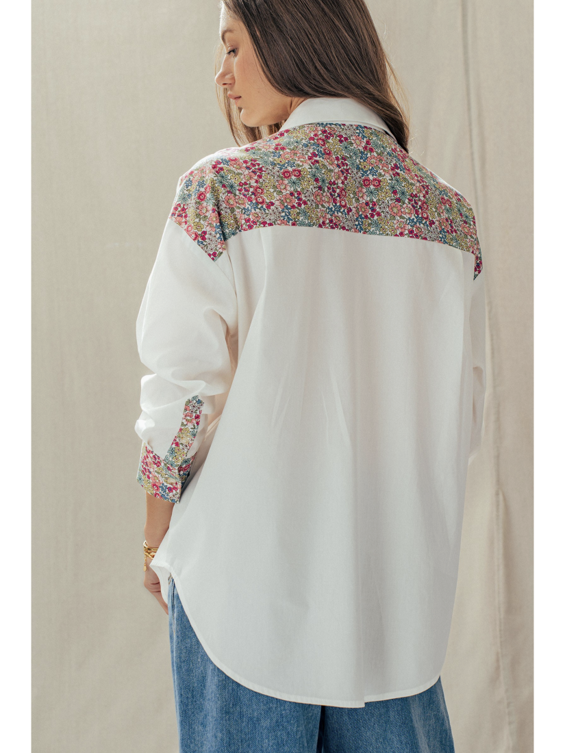 Woman wearing a white blouse with floral embroidery on a plain background