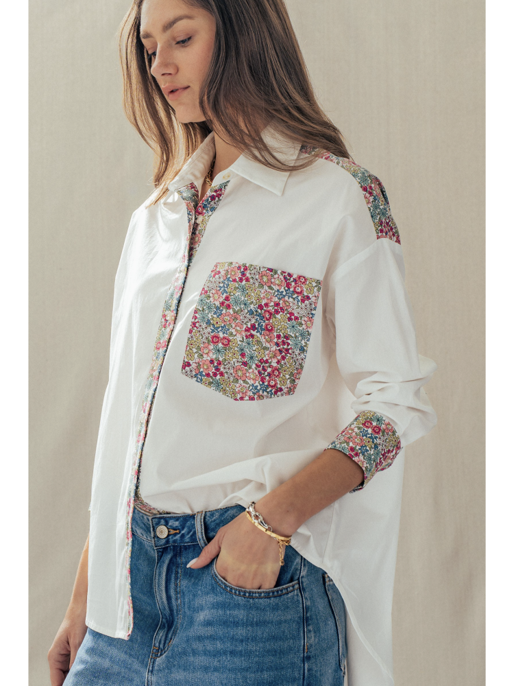 Woman wearing a white shirt with floral patterns on a plain background