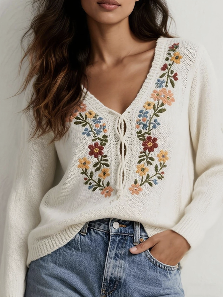 Cozy V-neck sweater featuring delicate colorful floral embroidery on the chest and sleeves for a whimsical, handcrafted look.