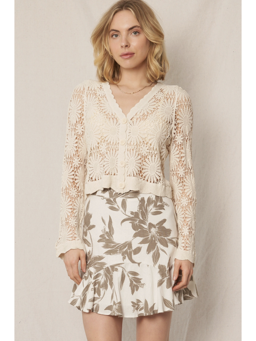 Model wearing a cream open-knit crochet cardigan with a floral sunburst pattern, scalloped edges, and long lace sleeves.