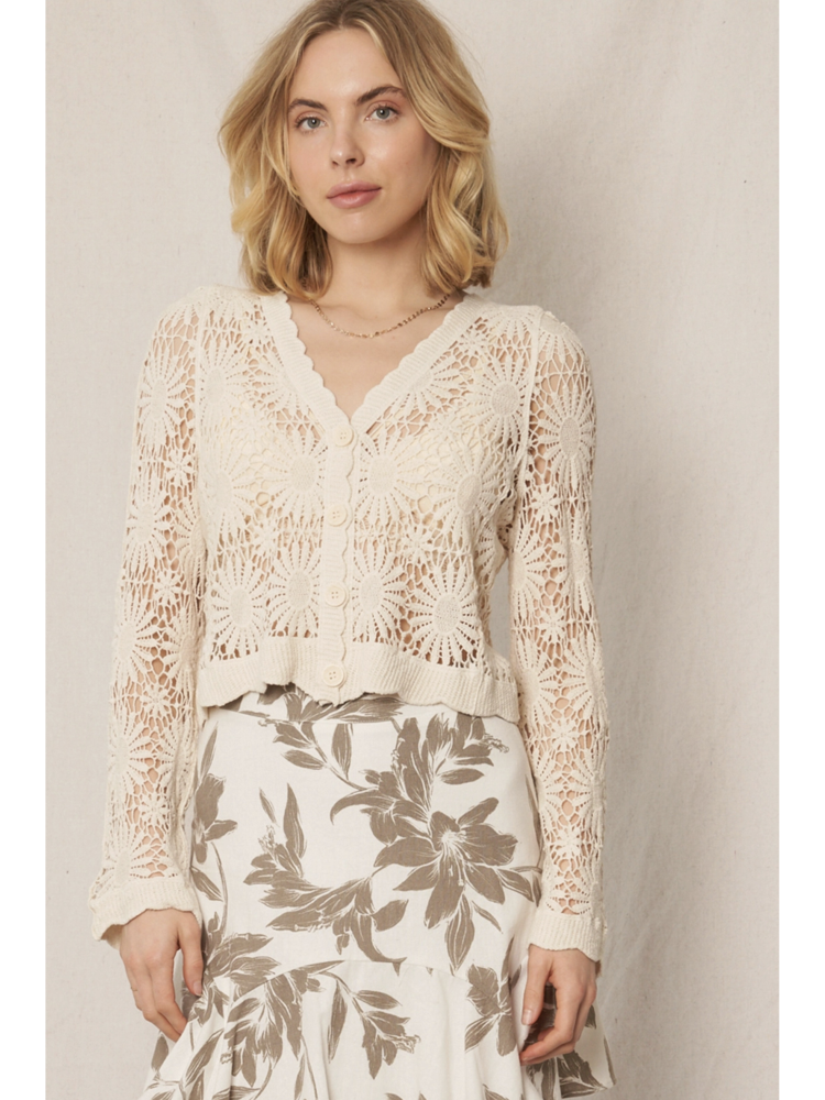 Model wearing a cream open-knit crochet cardigan with a floral sunburst pattern, scalloped edges, and long lace sleeves.