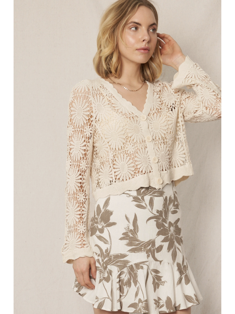 Model wearing a cream open-knit crochet cardigan with a floral sunburst pattern, scalloped edges, and long lace sleeves.