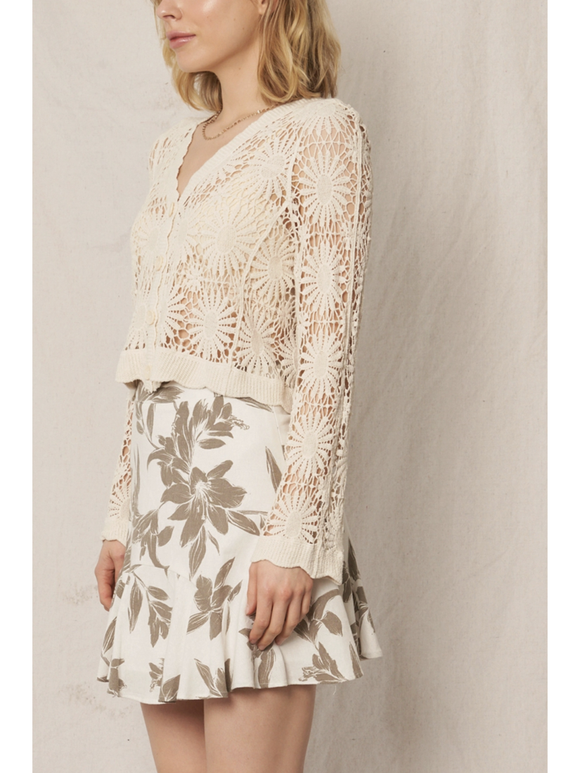 Model wearing a cream open-knit crochet cardigan with a floral sunburst pattern, scalloped edges, and long lace sleeves.