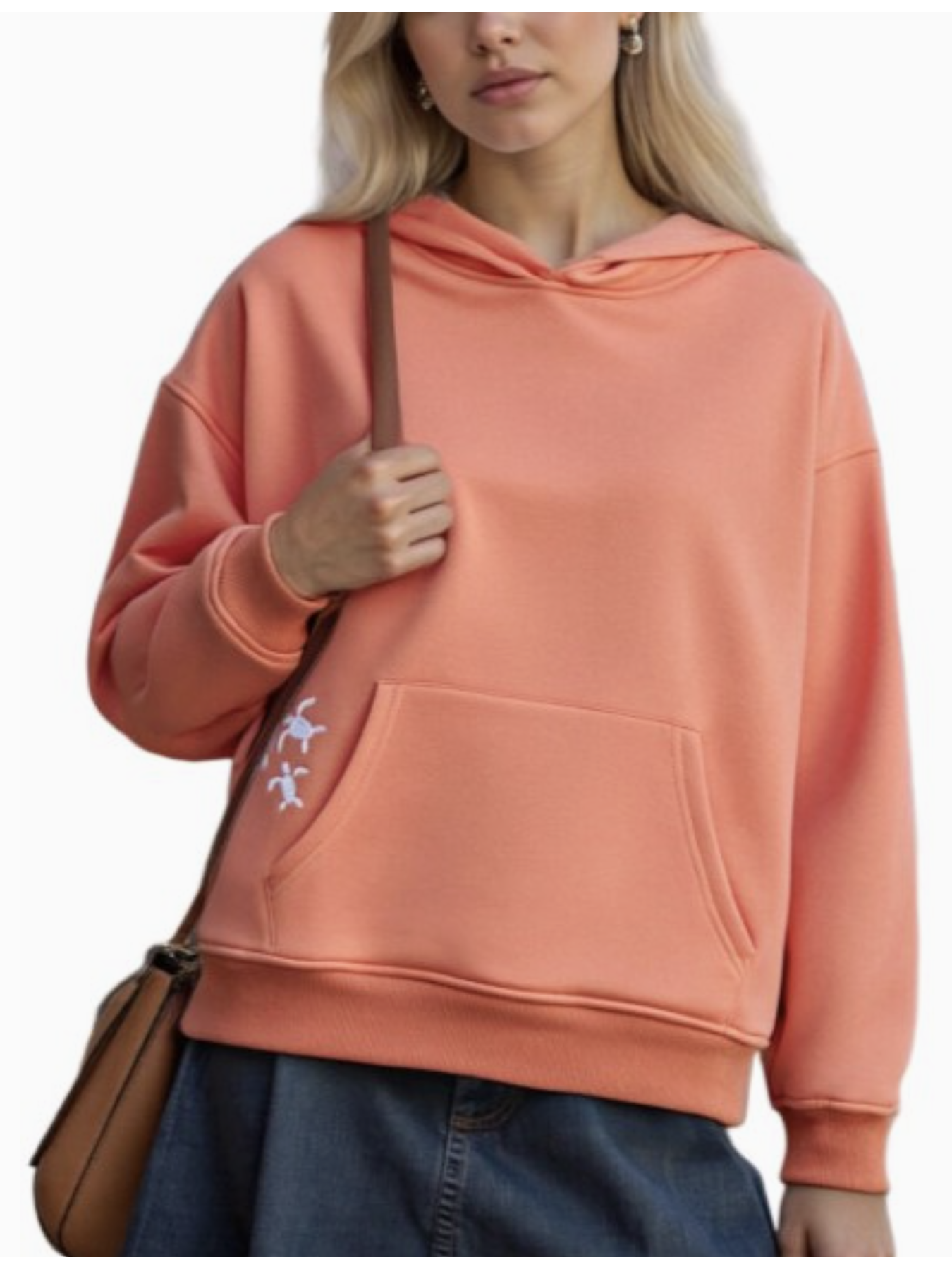 Woman wearing a salmon hoodie with a small design of sea turtles, holding a brown bag.