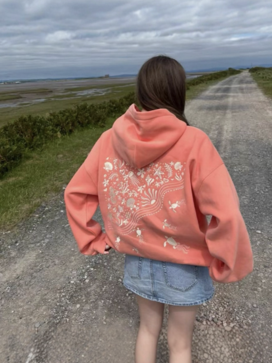 Person wearing a embroidered salmon hoodie with a scenic background