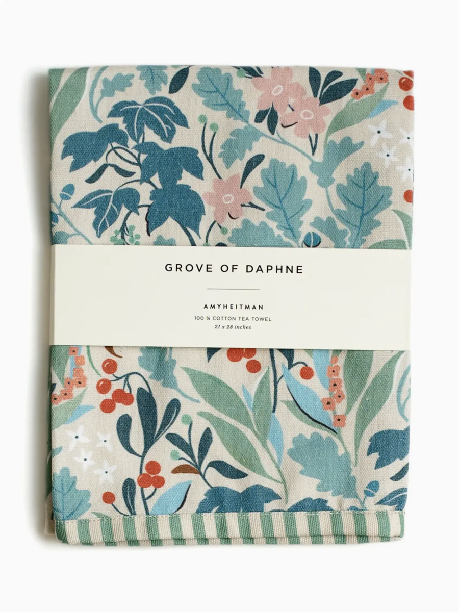 Whimsical watercolor tea towel featuring the 'Grove of Daphne' botanical print with lush green leaves and delicate flowers.