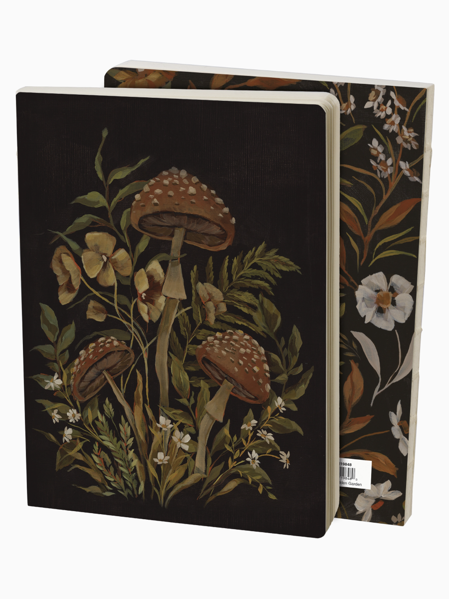 Hidden Garden Journal with dark covers featuring whimsical mushroom and flower illustrations with ferns and small white blooms.