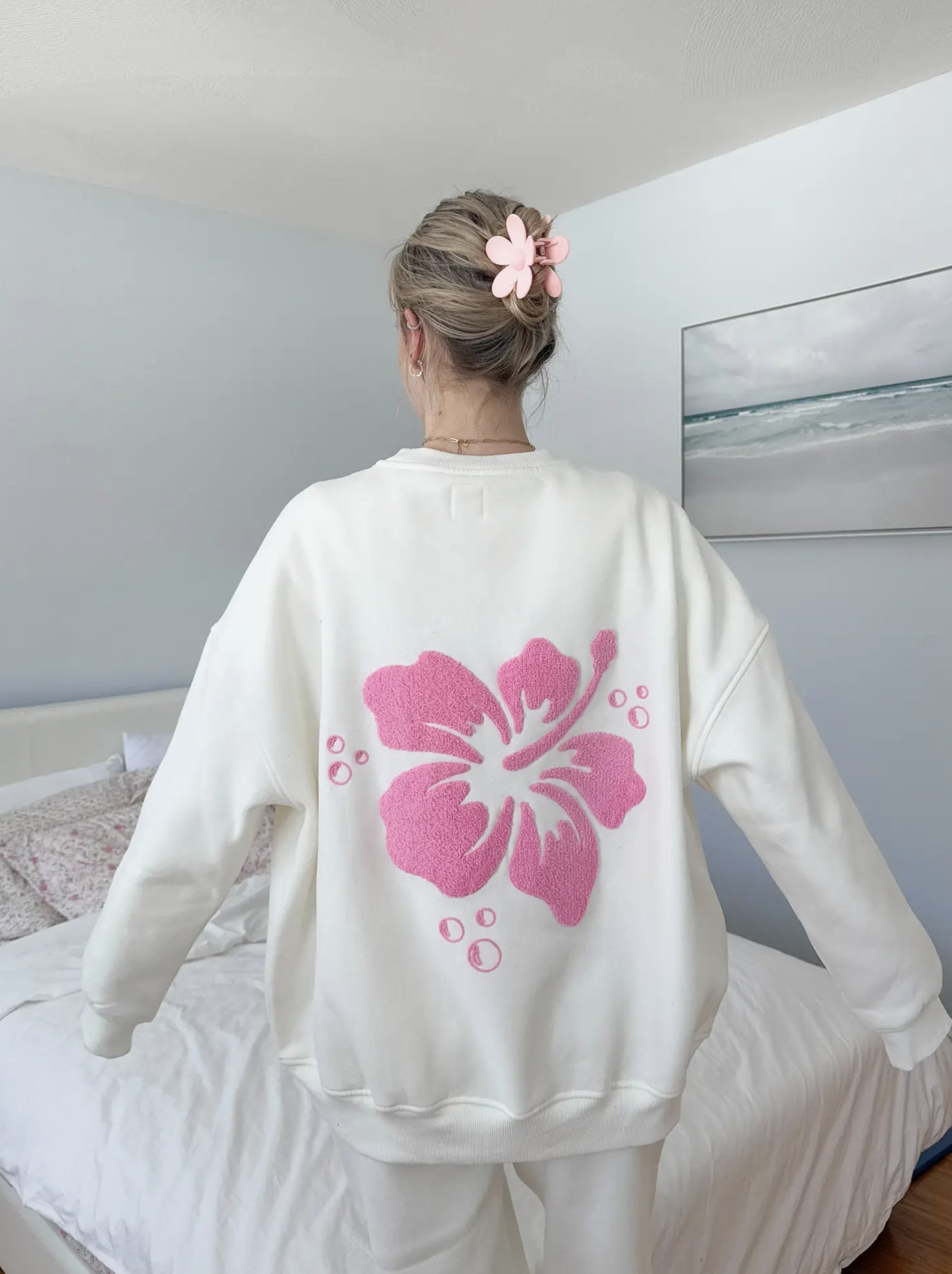 Ivory-colored sweatshirt featuring a vintage-style hibiscus flower graphic, perfect for a relaxed coastal and slow-living aesthetic.