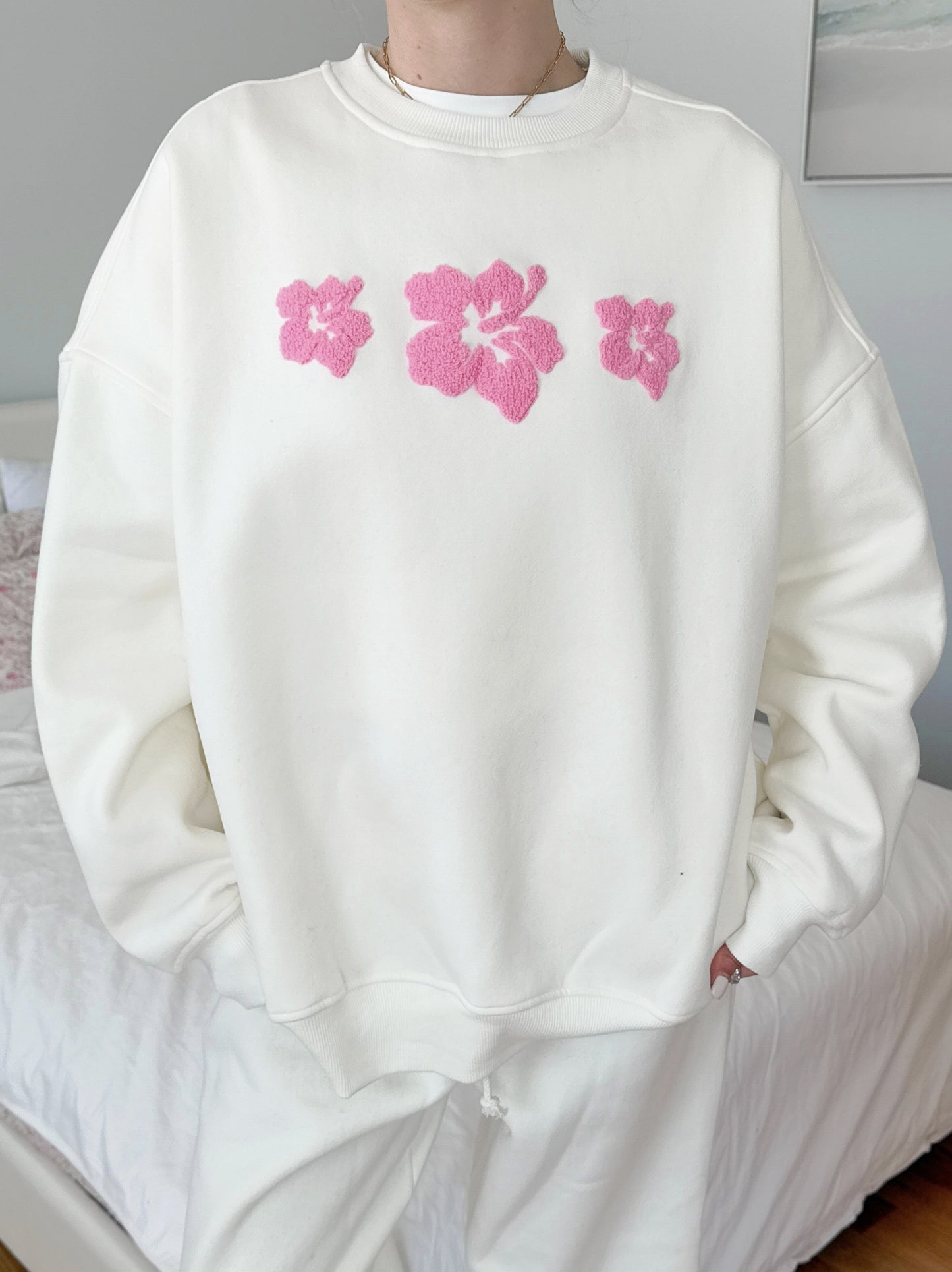 Ivory-colored sweatshirt featuring a vintage-style hibiscus flower graphic, perfect for a relaxed coastal and slow-living aesthetic.