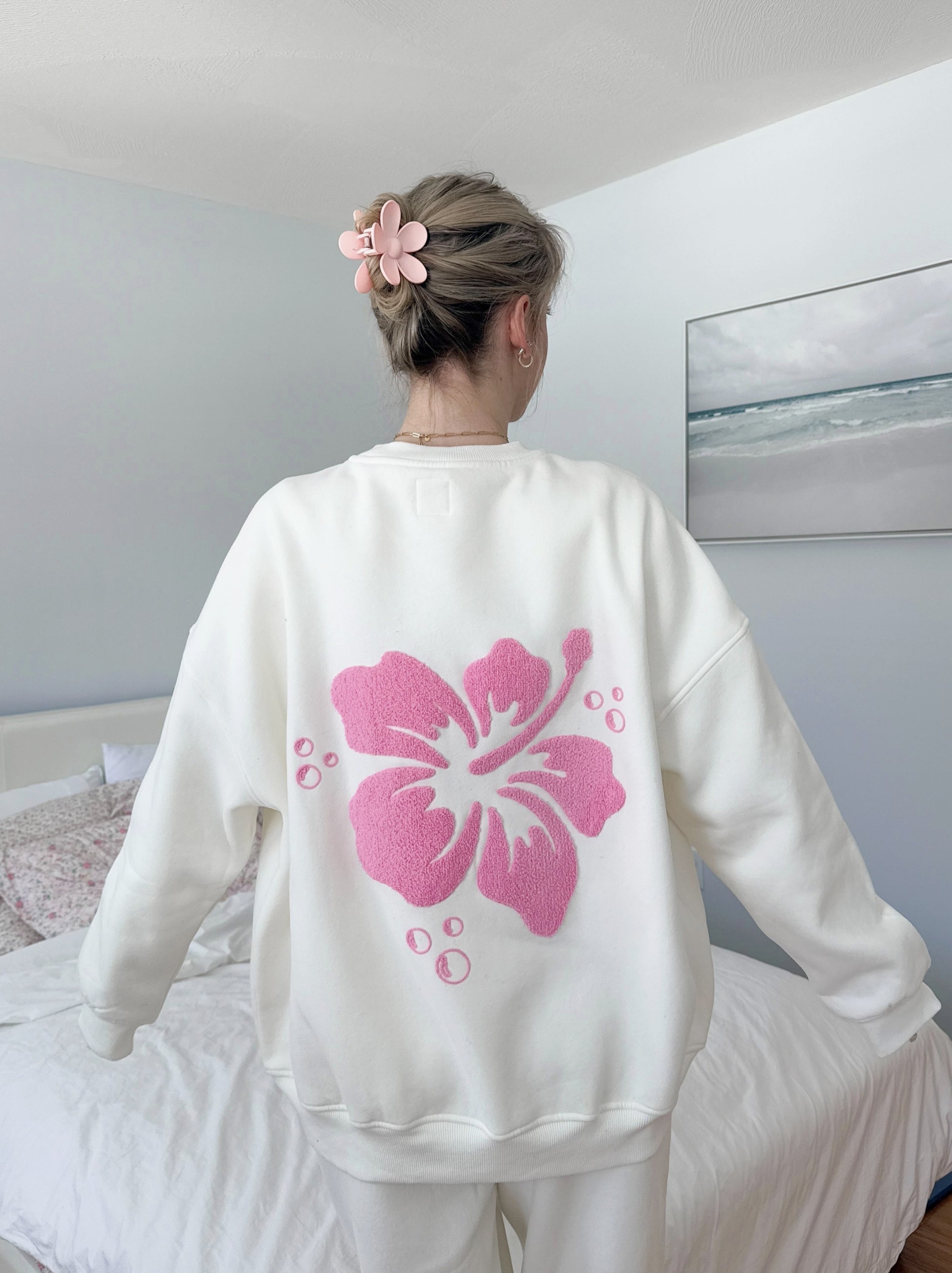 Ivory-colored sweatshirt featuring a vintage-style hibiscus flower graphic, perfect for a relaxed coastal and slow-living aesthetic.
