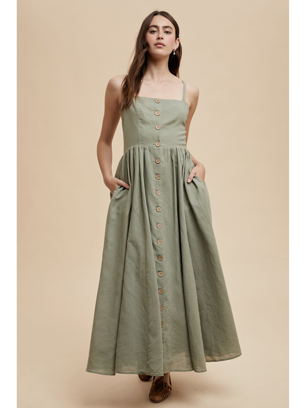 Woman wearing a green dress with buttons on a beige background