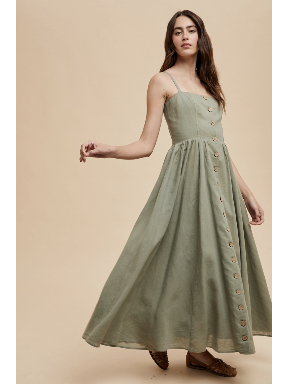 Woman wearing a green dress with buttons on a beige background