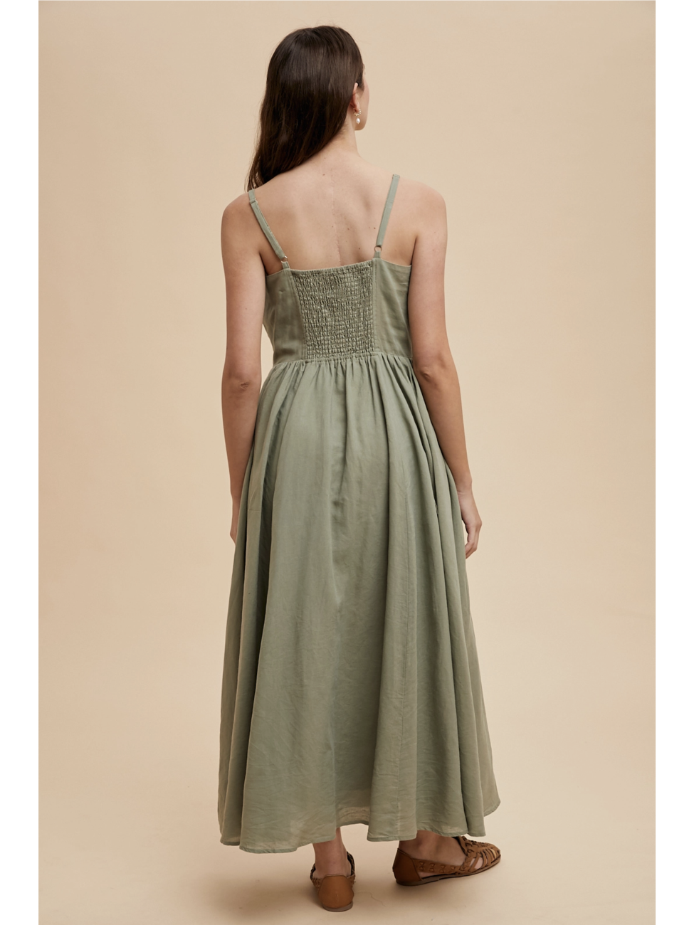 Woman wearing a green dress with buttons on a beige background