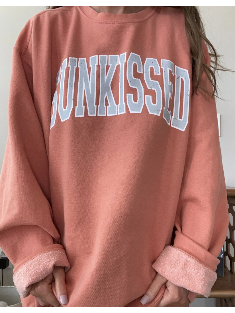 Relaxed-fit sweatshirt featuring a minimalist "Sunkissed" vintage graphic, perfect for a coastal and slow-living aesthetic.