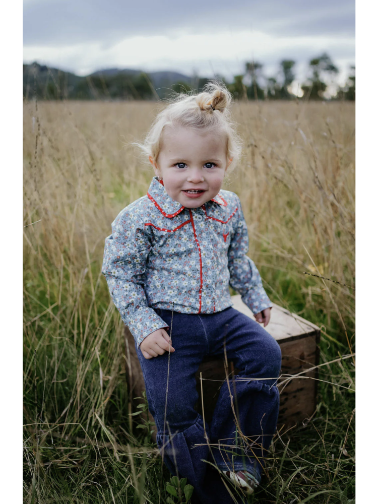 Child sitting on a wooden box in a grassy field