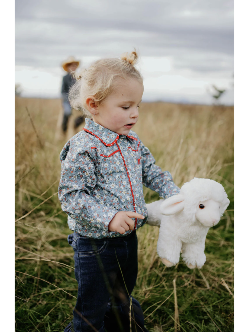 Child holding a stuffed animal in a field with a cloudy sky