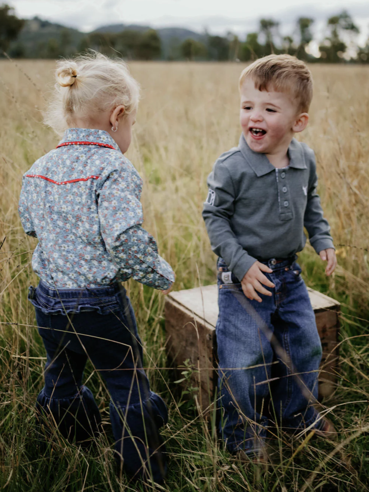 Two children playing in a field with a wooden box.