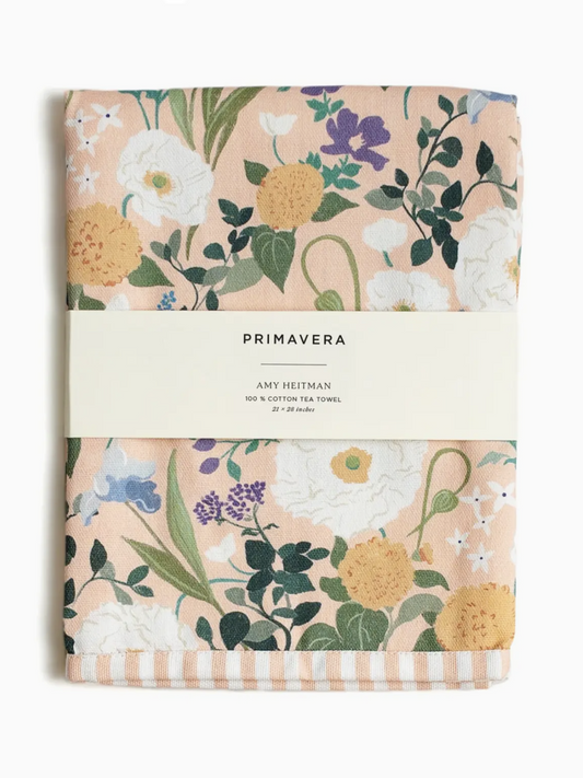 Watercolor floral tea towel with red poppies, yellow daisies, and blue flowers hanging in a bright kitchen.