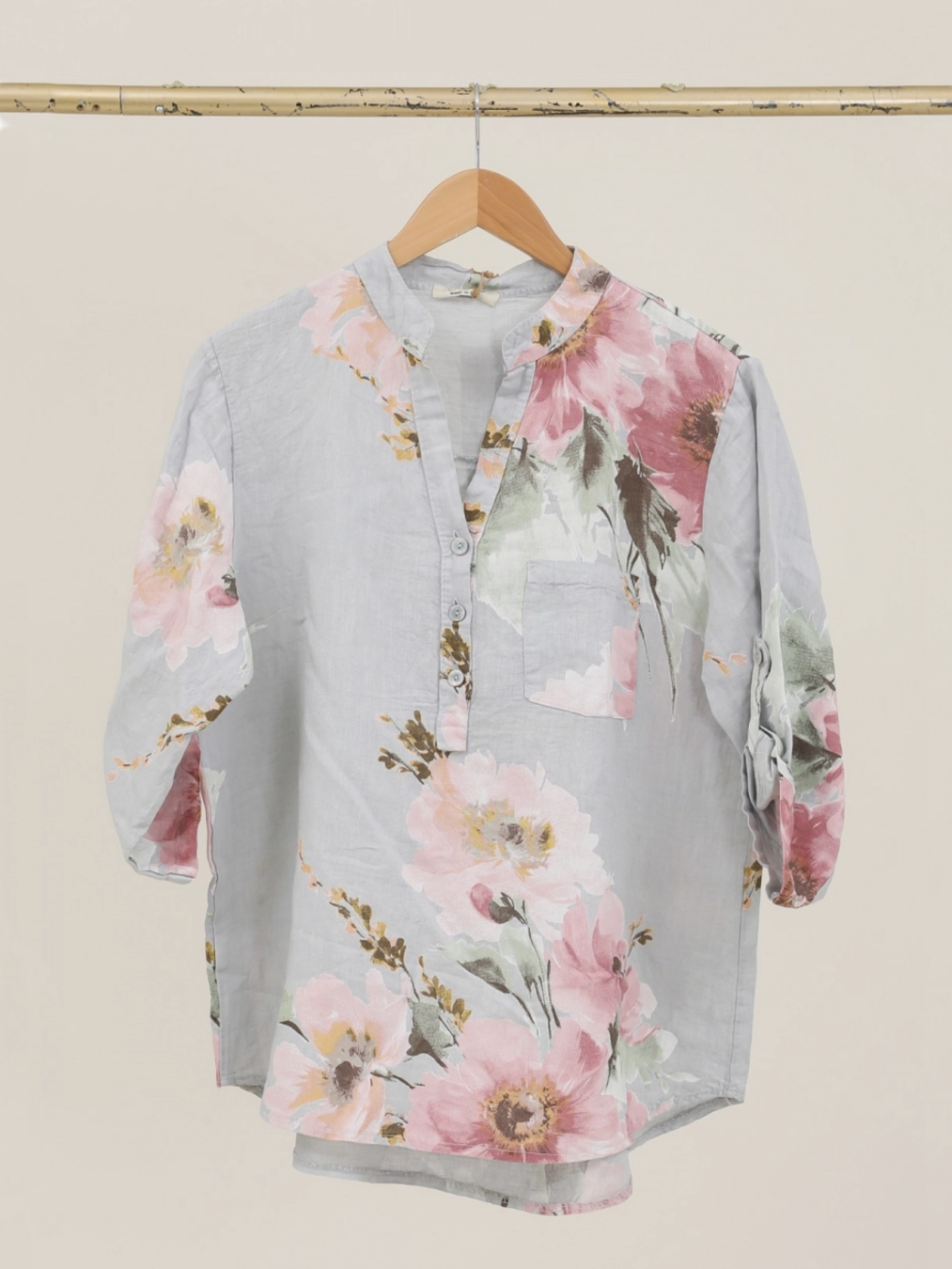 Floral blouse on a hanger against a neutral background