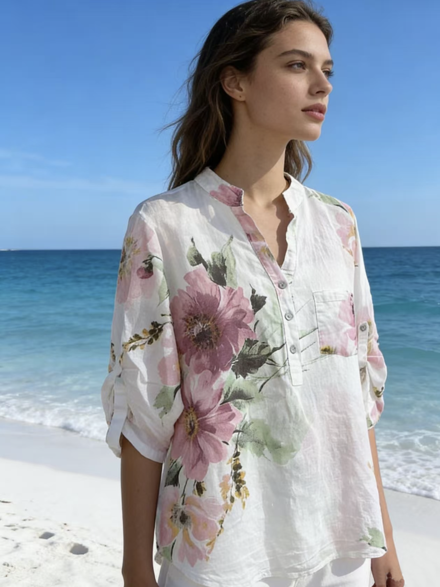 Woman wearing a floral shirt on a beach with ocean in the background
