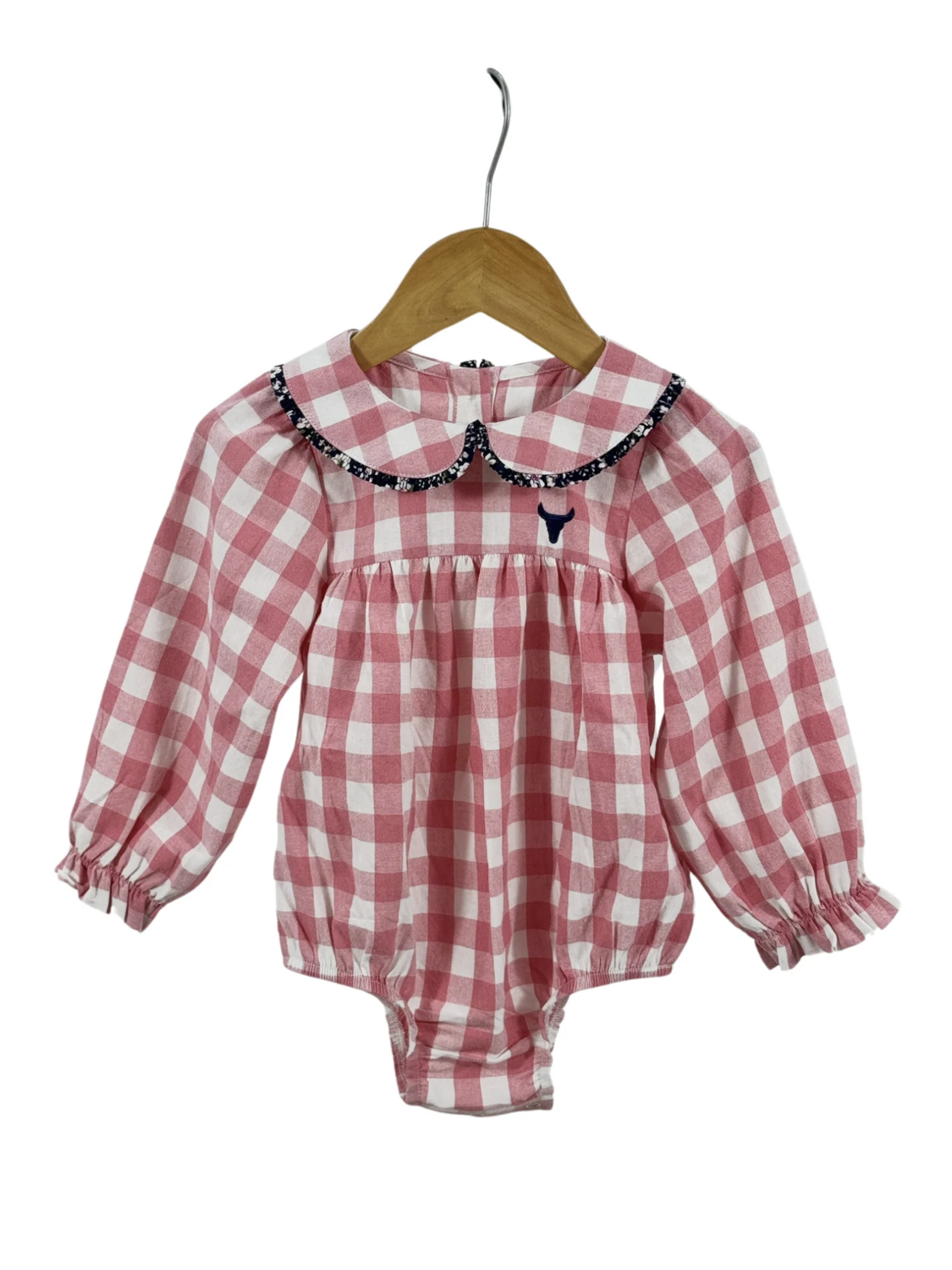 Pink and white gingham long-sleeve baby romper featuring a floral-trimmed Peter Pan collar and ruffled cuffs on a wooden hanger.