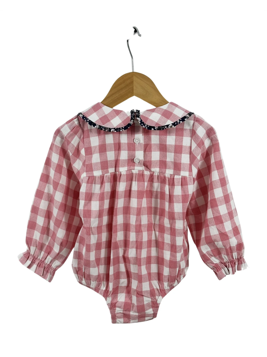 Pink and white gingham long-sleeve baby romper featuring a floral-trimmed Peter Pan collar and ruffled cuffs on a wooden hanger.