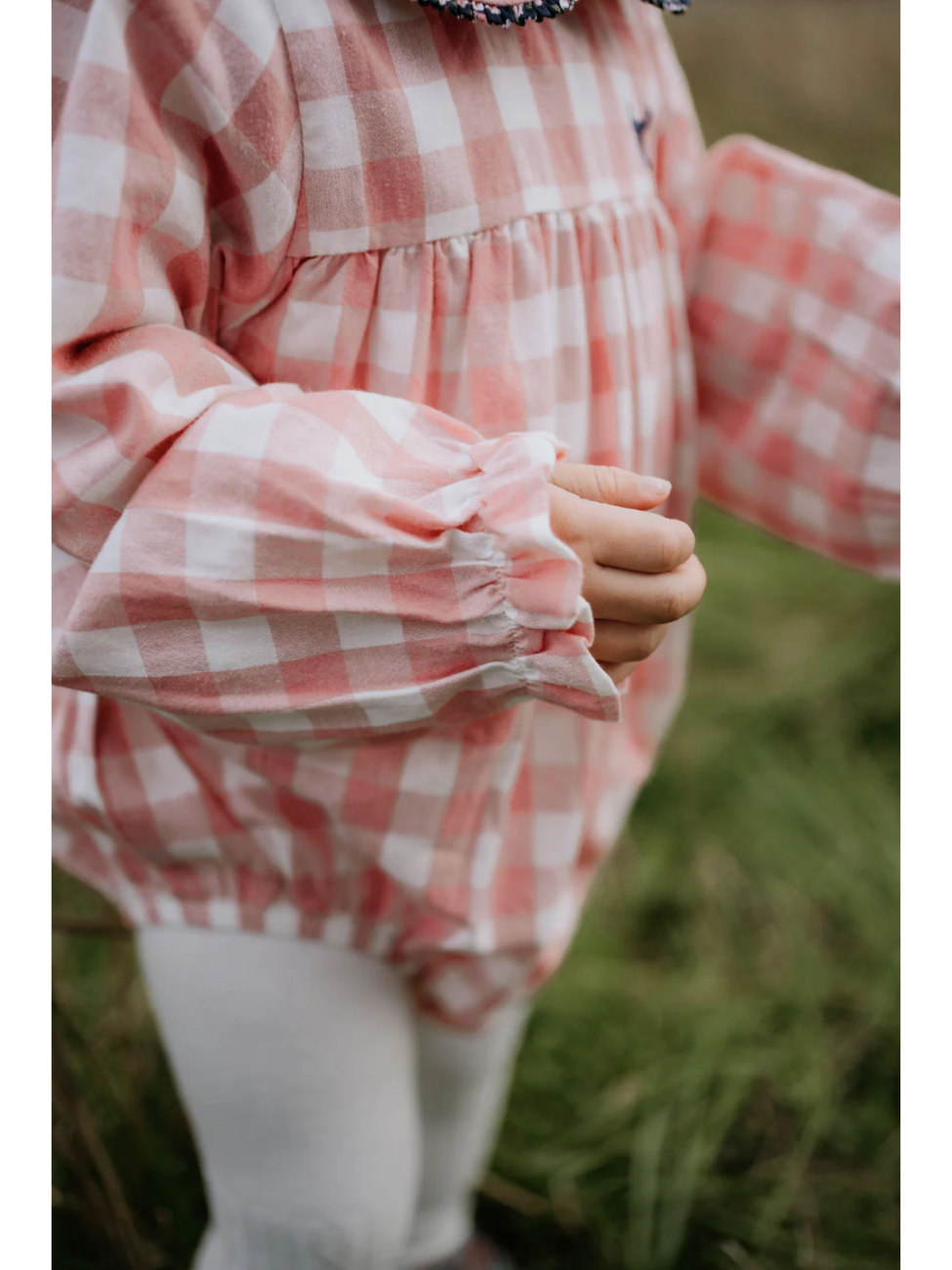 Person wearing a pink and white checkered dress in a natural setting
