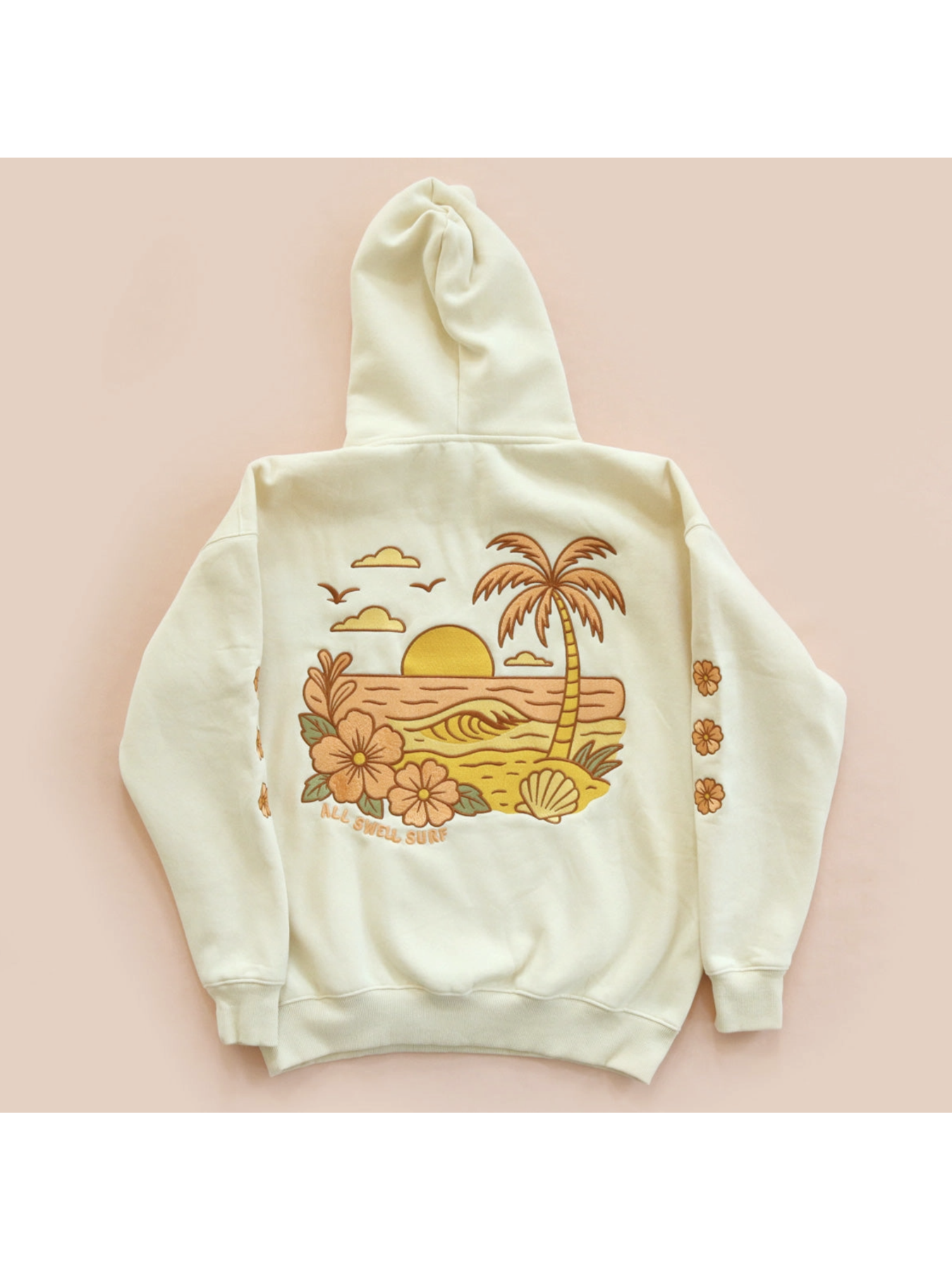 Cozy hoodie featuring a detailed embroidery of a coastal sunset over waves, designed for a whimsical and relaxed slow-living aesthetic.