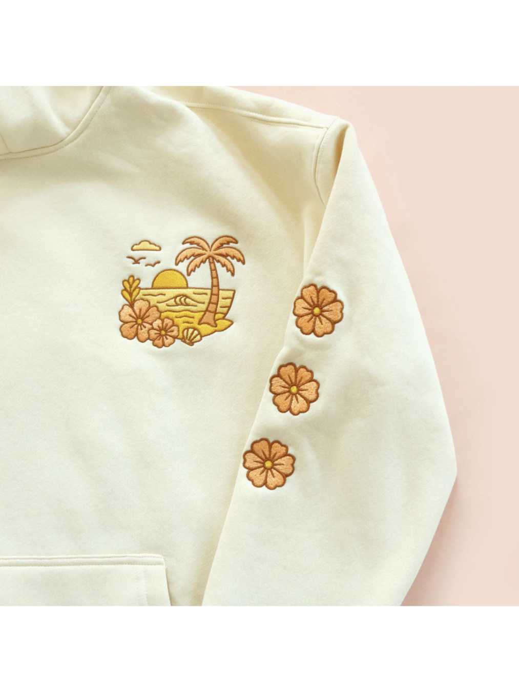Cozy hoodie featuring a detailed embroidery of a coastal sunset over waves, designed for a whimsical and relaxed slow-living aesthetic.