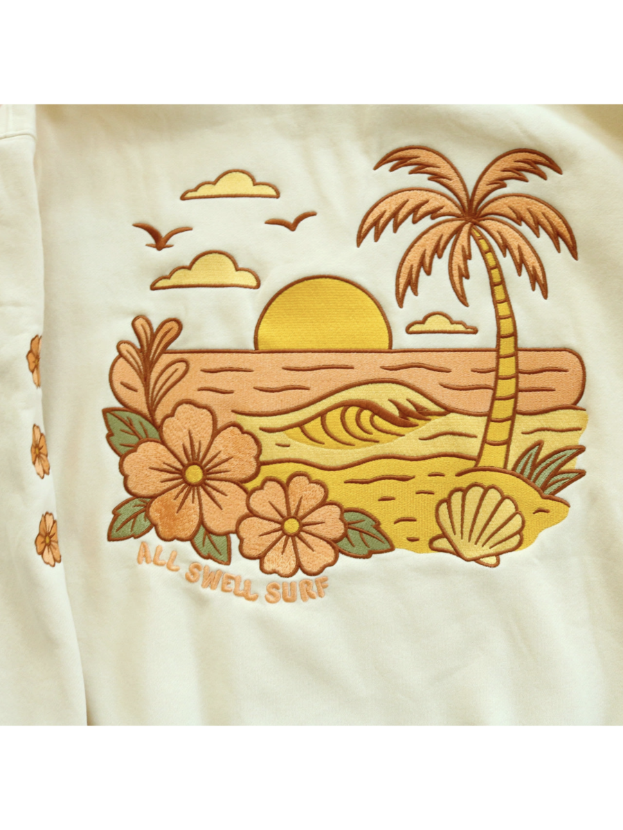Cozy hoodie featuring a detailed embroidery of a coastal sunset over waves, designed for a whimsical and relaxed slow-living aesthetic.
