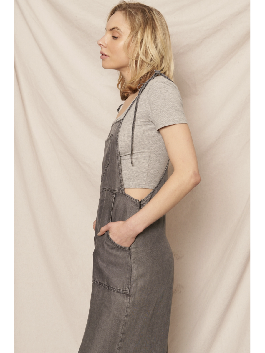 Black soft denim jumpsuit featuring adjustable tie shoulder straps, a square neckline, and a breezy wide-leg silhouette on a model.
