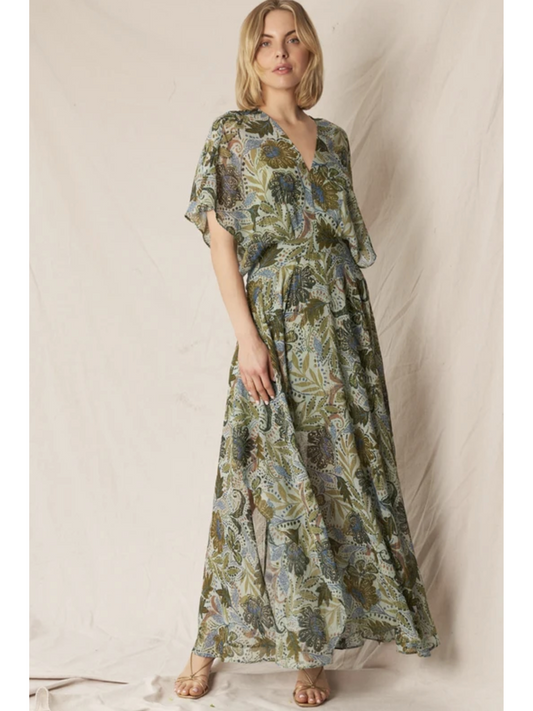 Model in a dark floral print gauze maxi dress with a V-neckline, long sleeves, and a tiered skirt, standing against a neutral background.